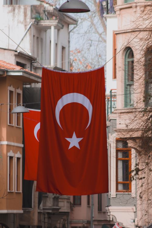 Free Prominent Turkish flags elegantly hang in a vibrant city street, showcasing patriotism. Stock Photo