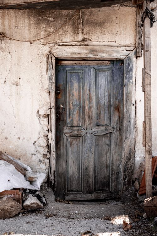 Free A rustic wooden door on an old, weathered facade, reflecting decay and abandonment. Stock Photo