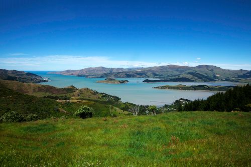 Free Scenic view of a coastal landscape with green hills and blue sea under a clear sky. Stock Photo