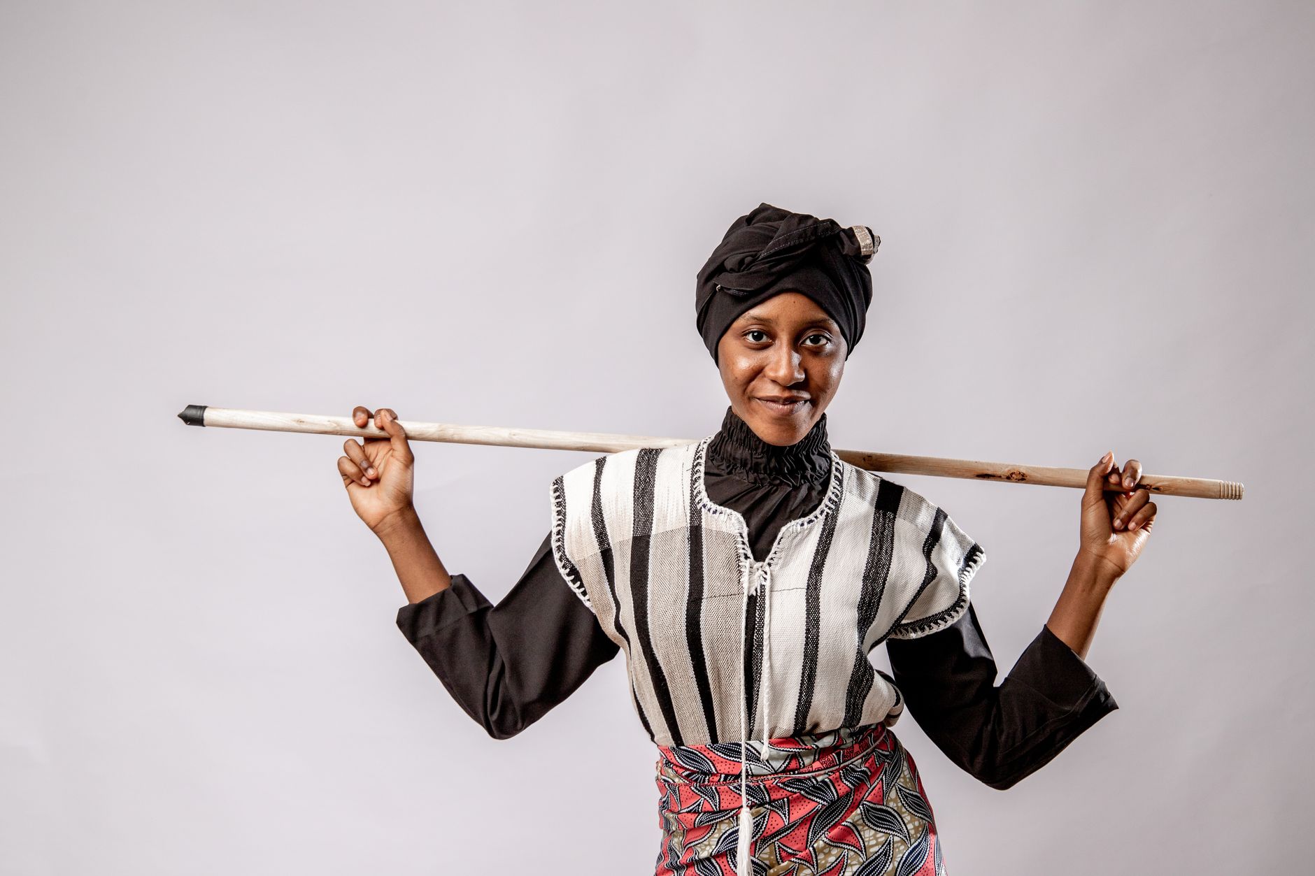Portrait of an African woman in traditional attire holding a staff, showcasing tribal culture.