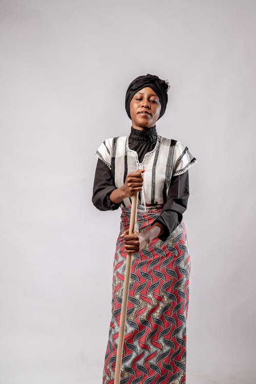 Studio Portrait of a Woman Wearing Traditional Clothes Holding a Pole