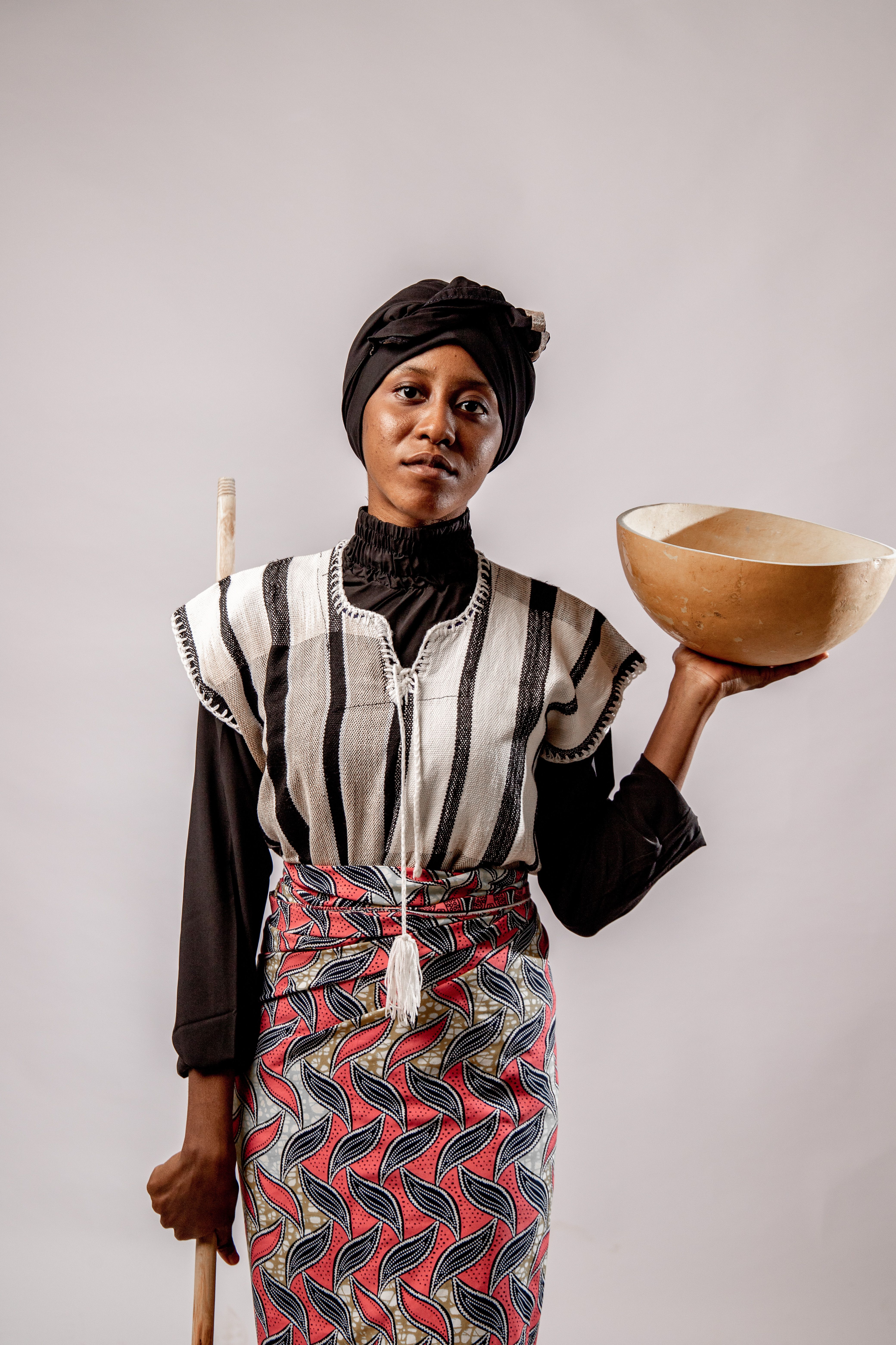 Portrait of an indigenous woman holding a bowl and a pole, Guinea