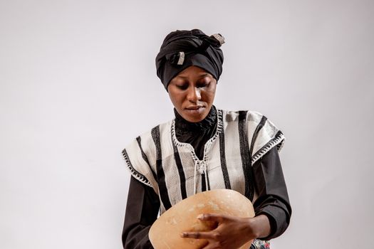 A young woman in traditional attire holding a bowl against a white studio background.