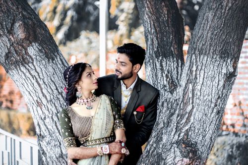 Free Romantic Indian couple in traditional wedding attire embracing outdoors by a large tree. Stock Photo