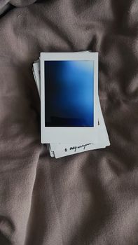 A stack of Polaroid photos lying on soft fabric, capturing a moody, artistic vibe.
