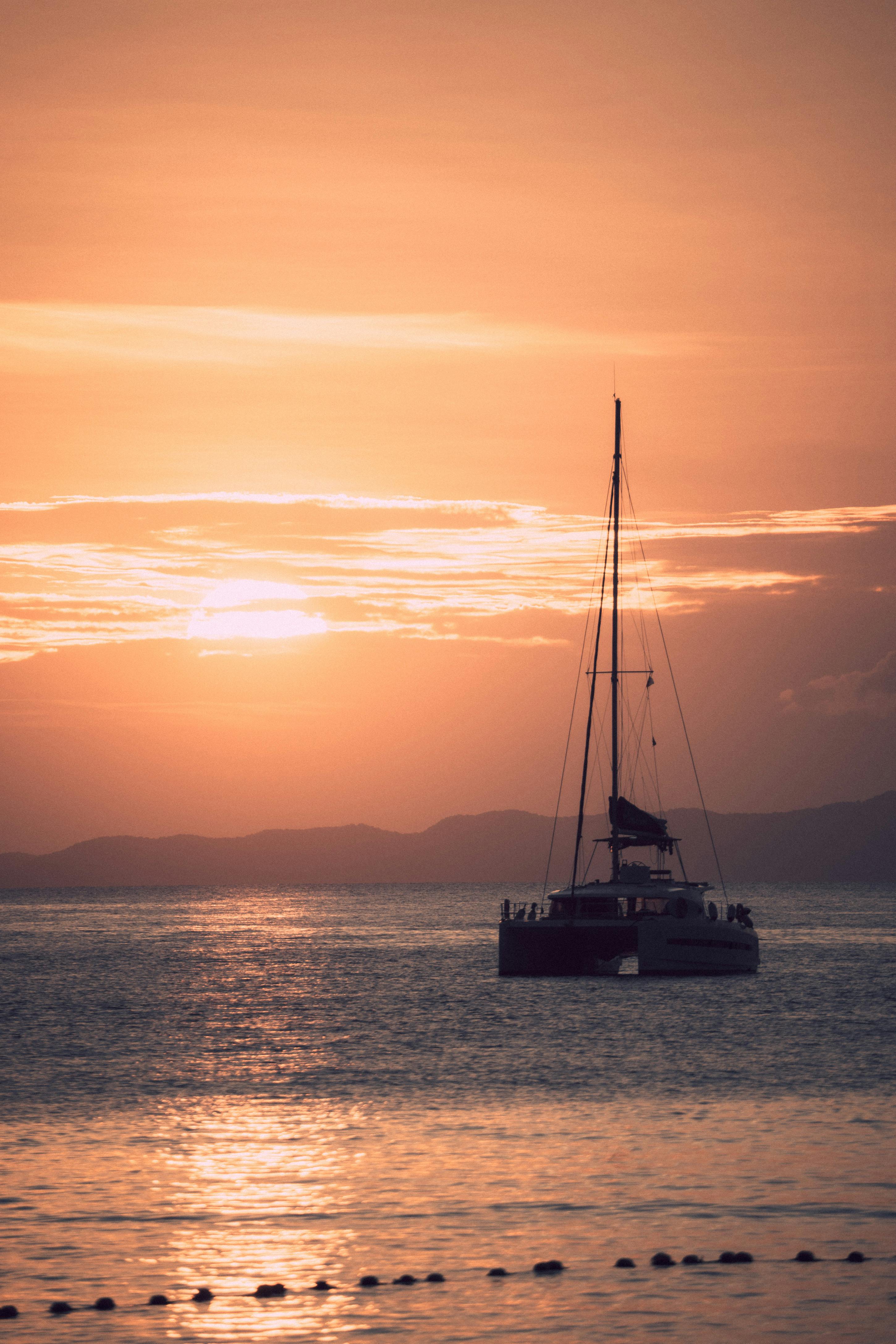 A stunning silhouette of a sailboat cruising at sunset in Ao Nang, Thailand's serene waters.