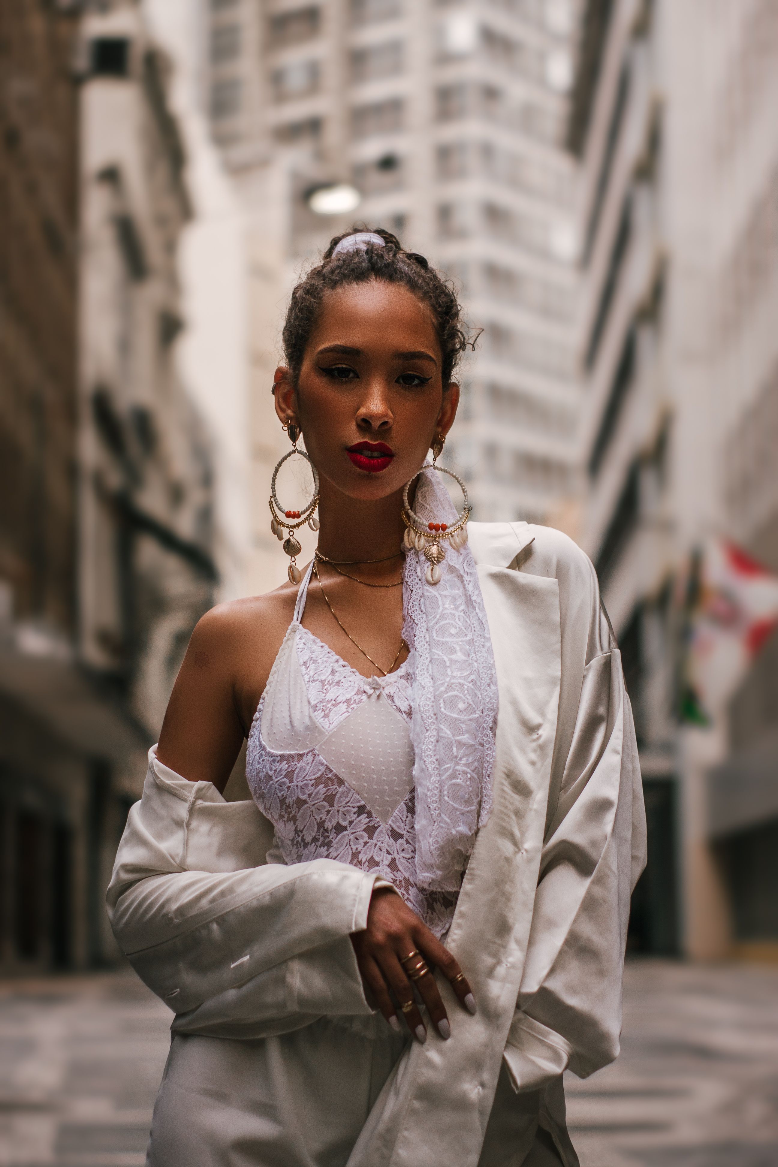 Mulher elegante em traje branco posando confiantemente em uma rua da cidade.