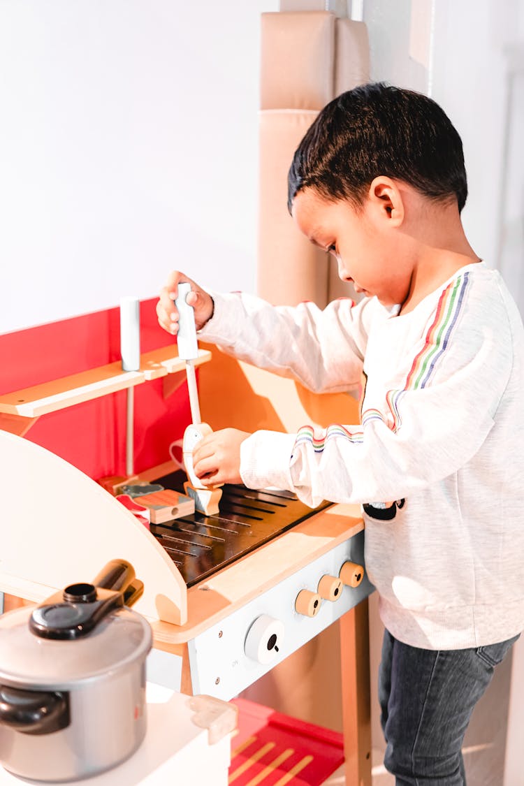 A Toddler Playing With A Mini Kitchen Set