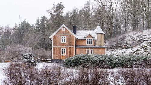 Free Charming wooden cottage surrounded by snowy countryside, creating a serene winter scene. Stock Photo
