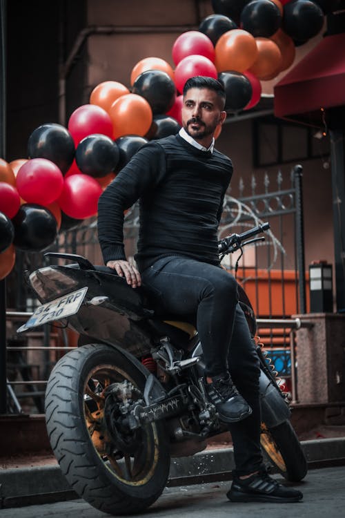 Man Sitting on a Motorbike in Front of Balloons 