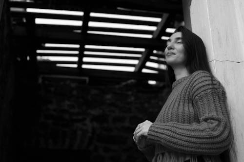 Free Brunette Woman in Sweater Standing by Wall Stock Photo