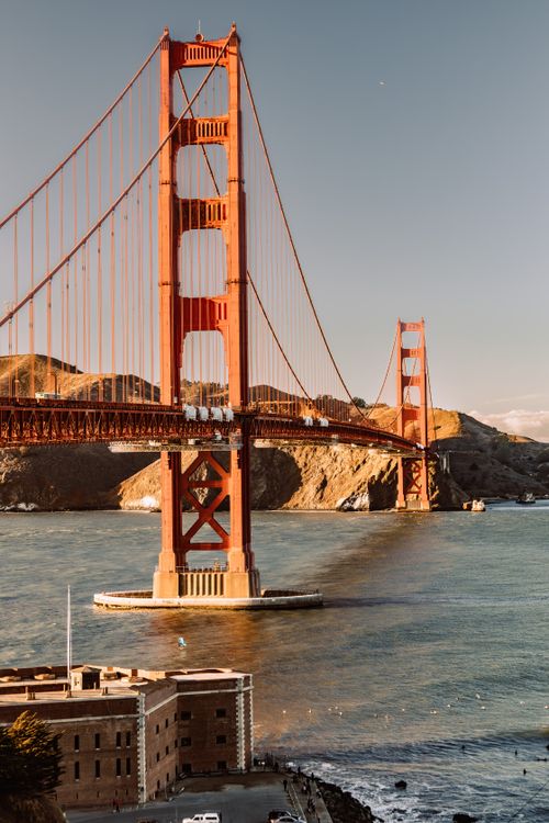 Free Captivating sunset view of the iconic Golden Gate Bridge in San Francisco with calm sea waters. Stock Photo
