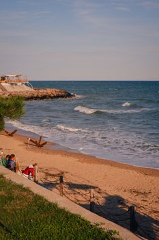 Tranquil beach scene with ocean waves and people relaxing at sunset.