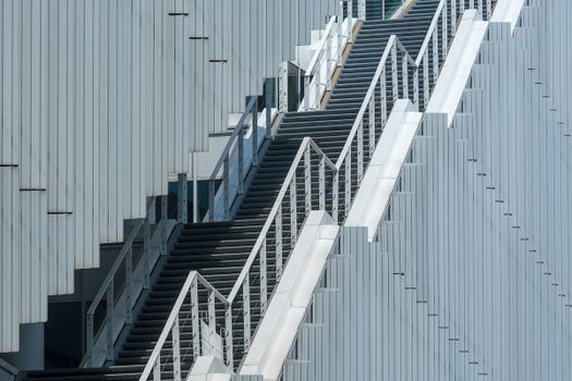 Sleek metal staircase against a modern building facade in an urban environment.