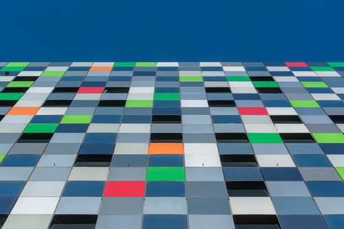 Free A vibrant facade showcasing modern architecture with colorful geometric patterns against a clear blue sky. Stock Photo