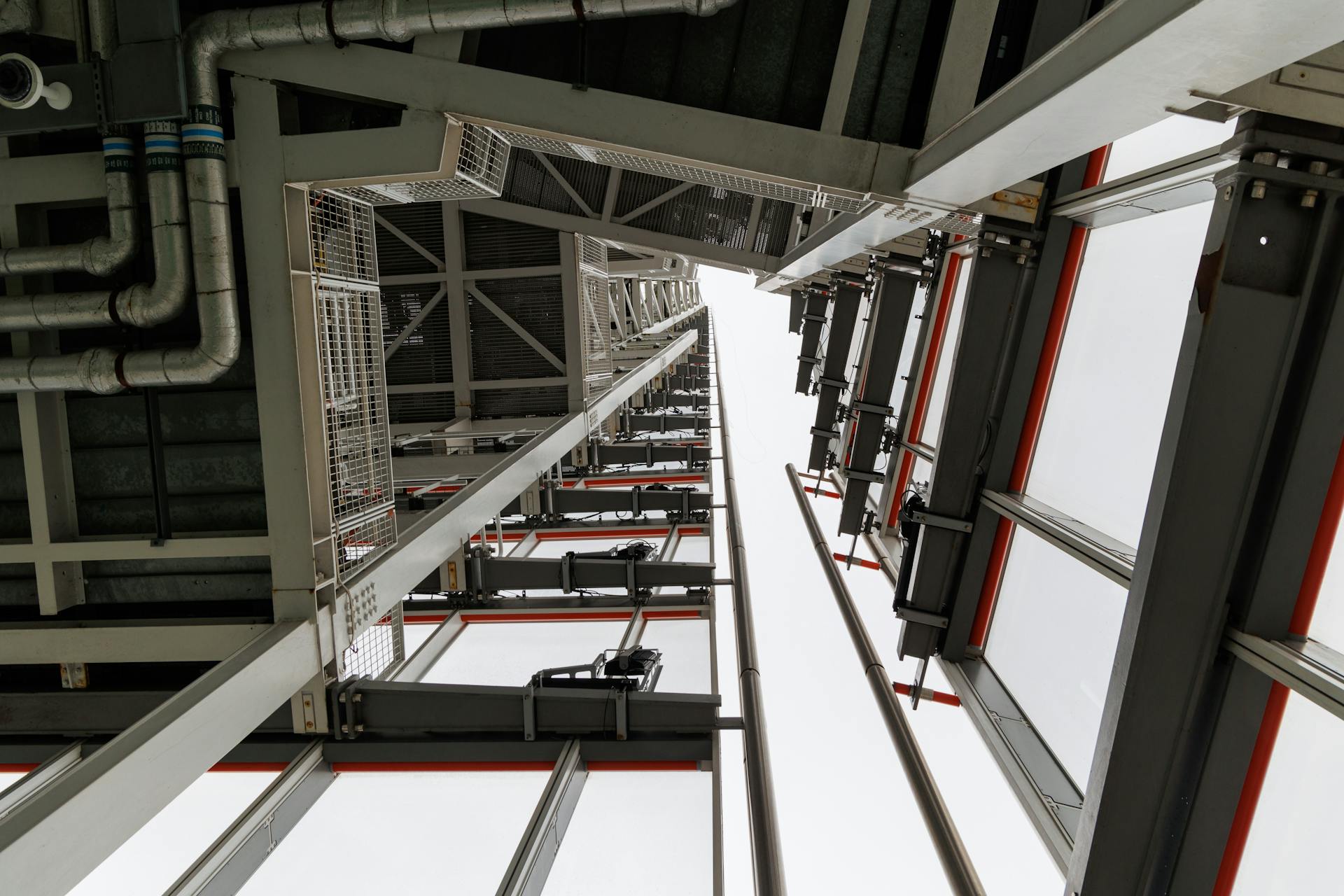 Low angle shot of a steel and glass structure showcasing pipes and industrial design elements.