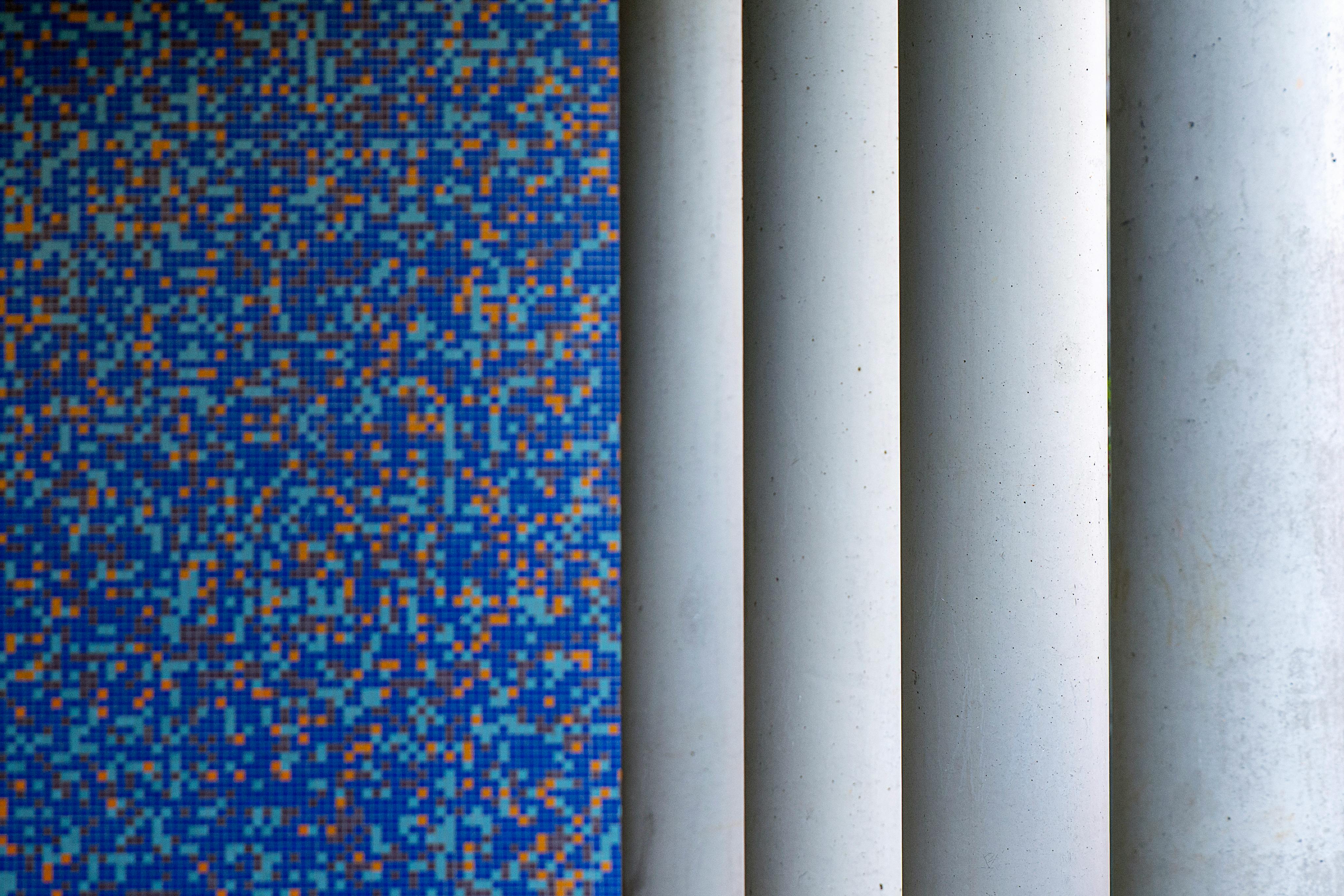 A creative composition featuring vibrant blue mosaic tiles juxtaposed with white columns.