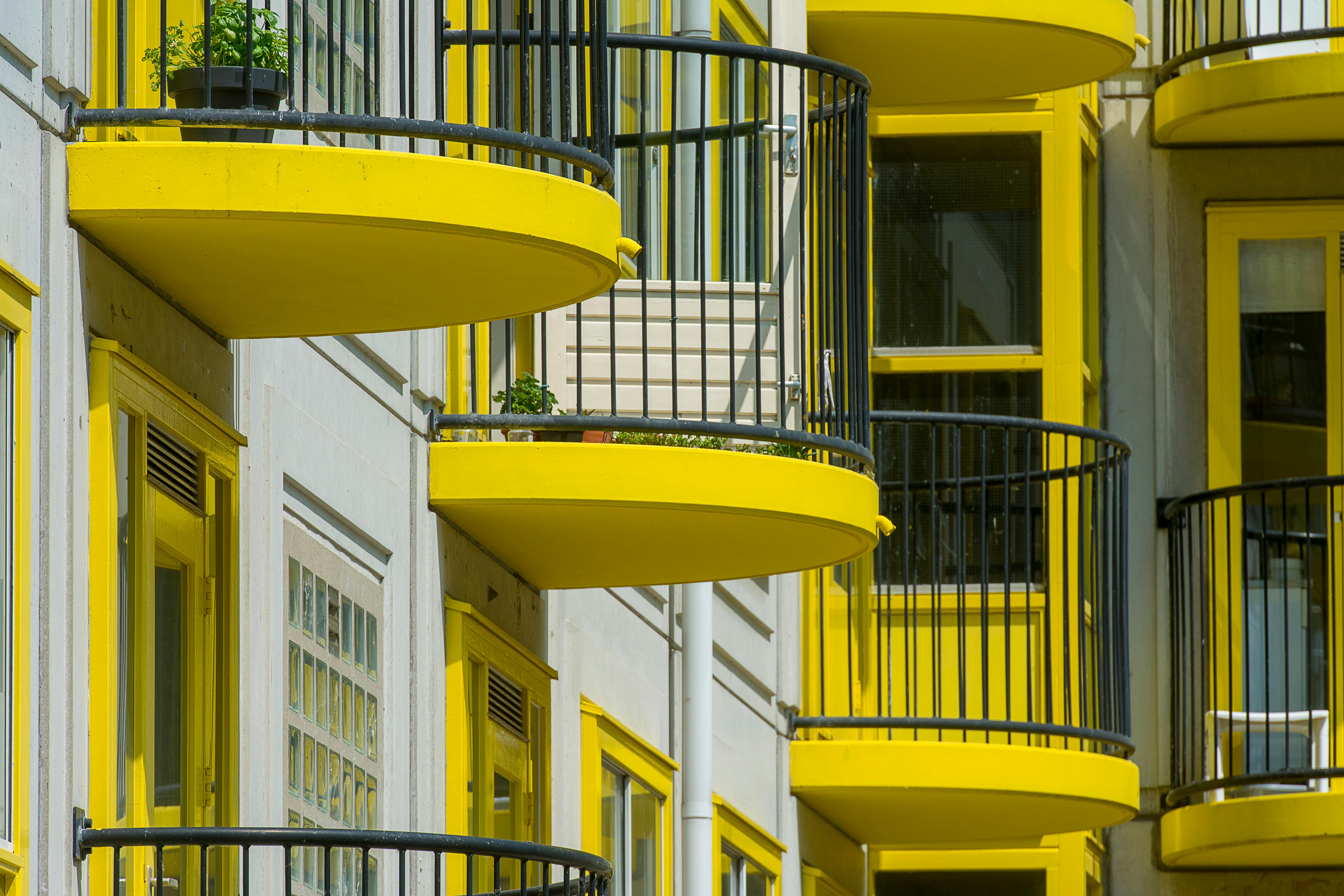Close-up of modern yellow balconies on an urban apartment building facade.
