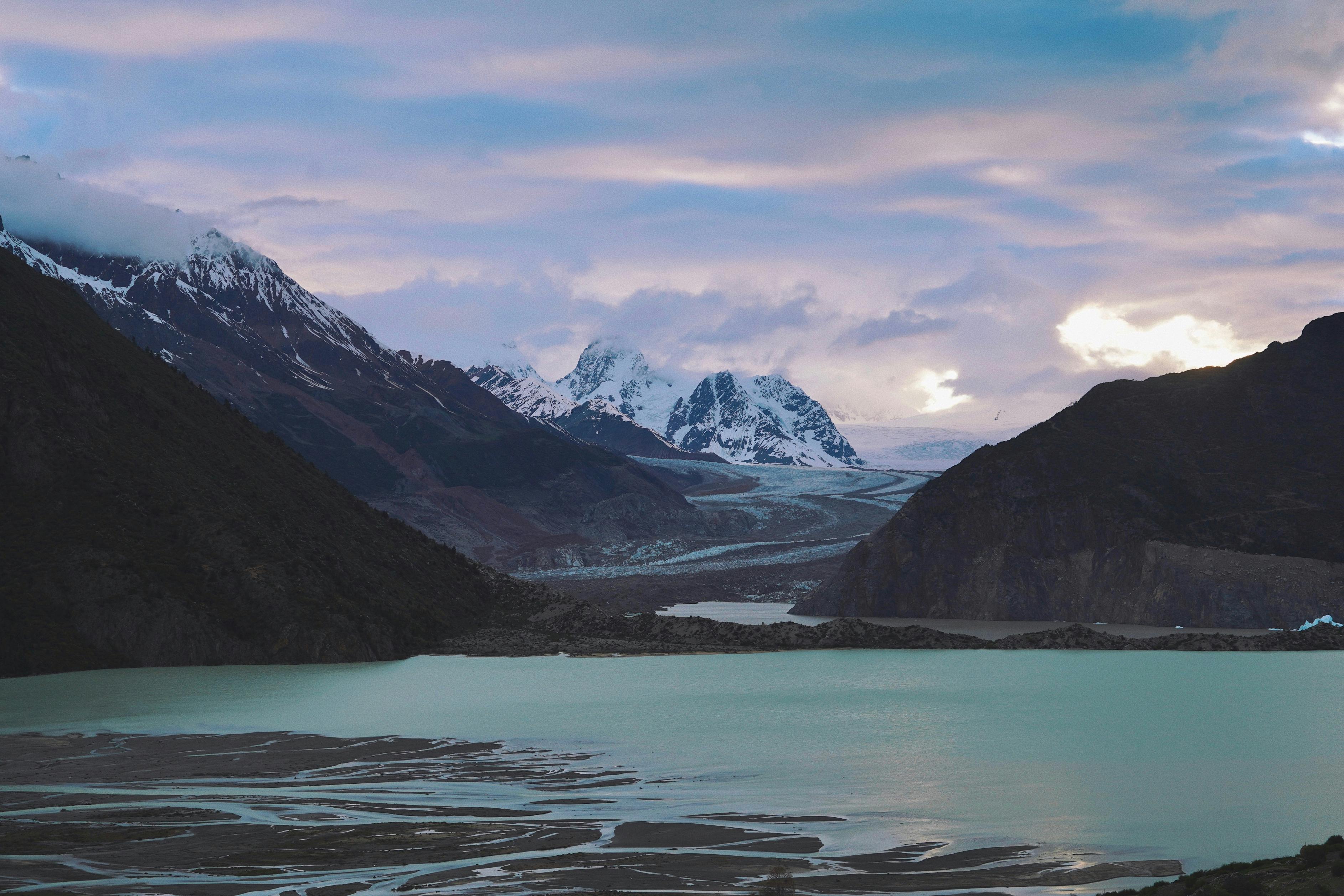 Breathtaking view of a mountain lake and glacier in Lhasa, Tibet with dramatic skies.