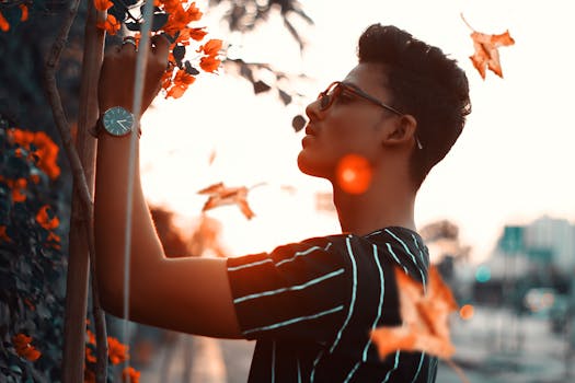 日落时分，一位戴着太阳镜的时尚男子在秋日背景下拍摄的肖像