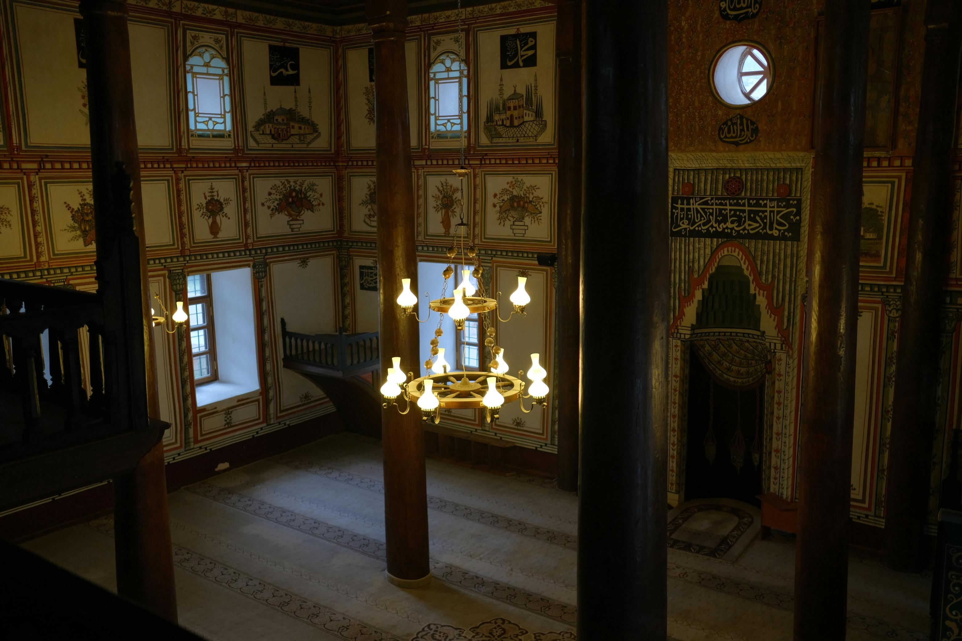 Elegant Ottoman mosque interior with intricate decor and chandeliers, showcasing Islamic architecture.