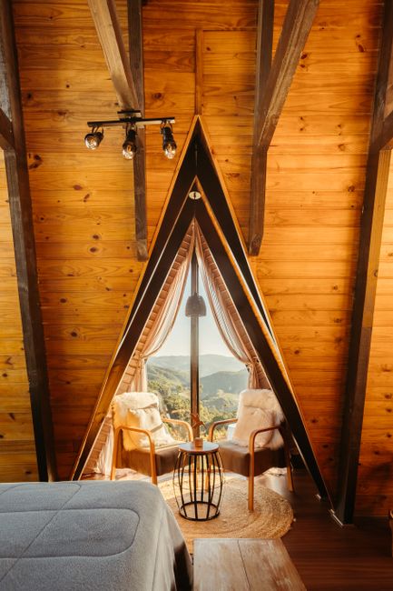 Warm A-frame cabin interior with window view of mountains.