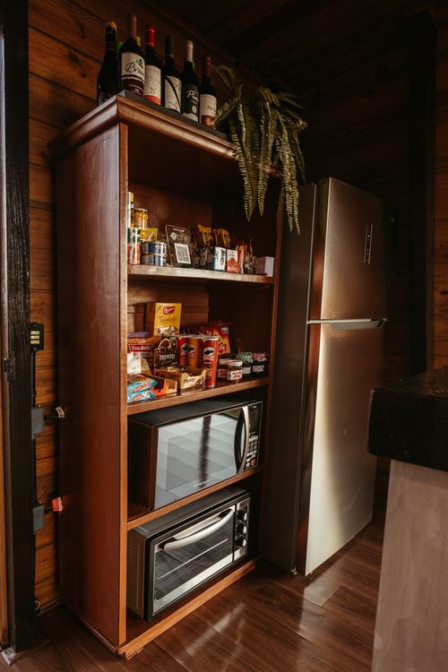 Free Wooden shelf with snacks and wine, next to modern fridge, in a rustic kitchen setting. Stock Photo