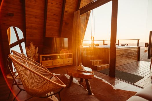 Warm and inviting rustic living room featuring wooden interiors and terrace at sunset.