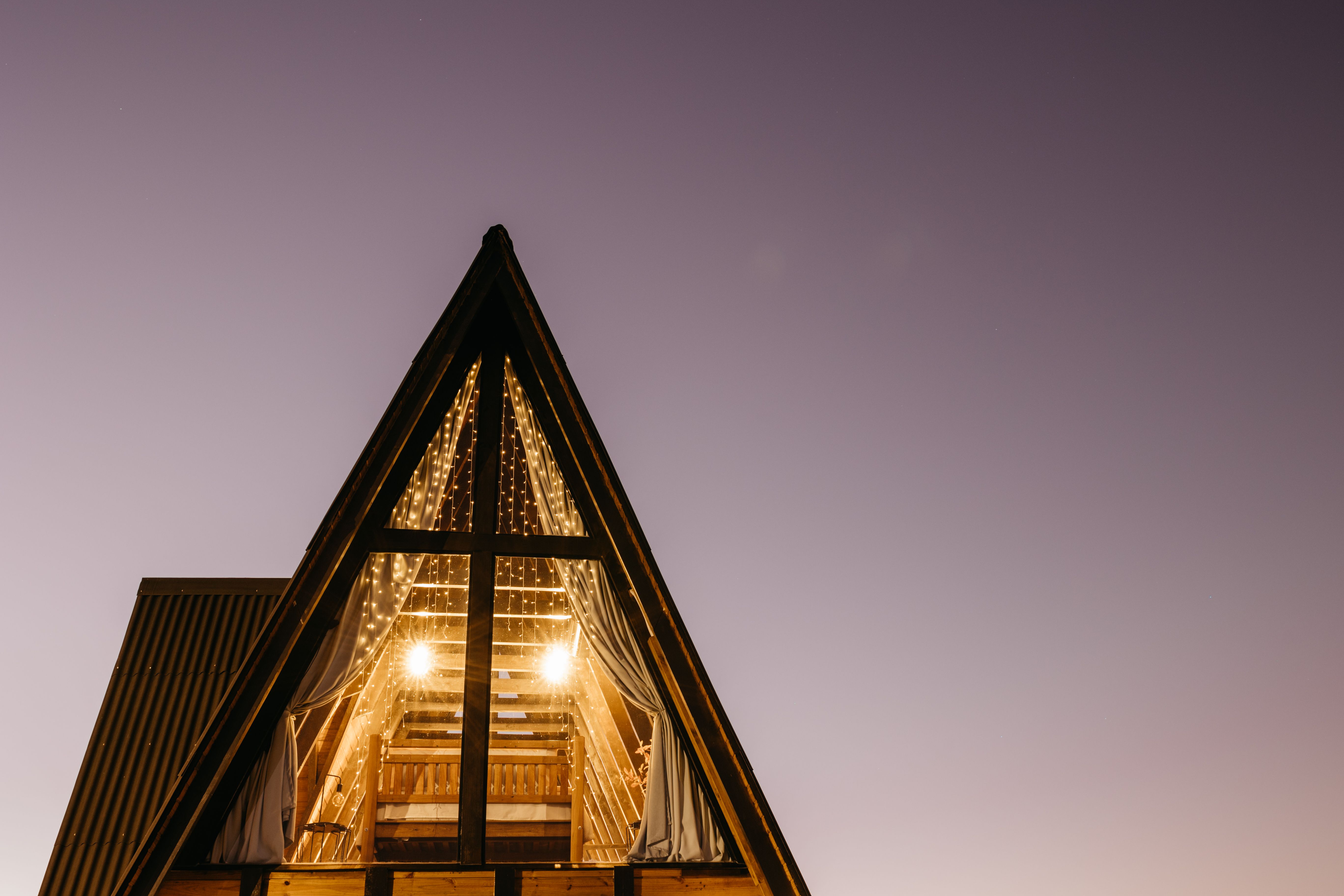 A beautiful A-frame cabin glowing with lights under the twilight sky, creating a serene ambiance.