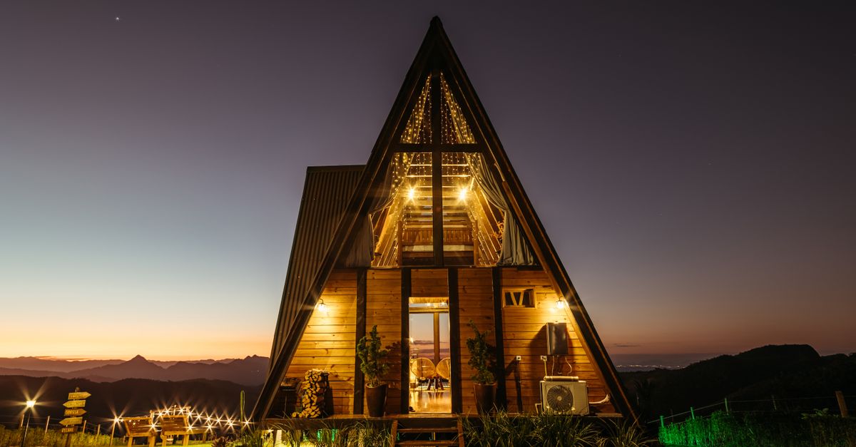 An upscale A-frame cabin illuminated at night with mountain views.