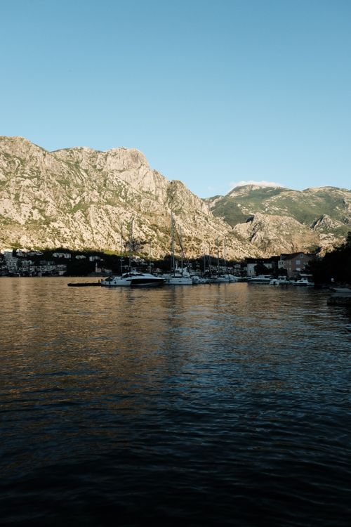 Free Scenic photo capturing the tranquil Kotor Bay with majestic mountains and moored boats in Montenegro. Stock Photo