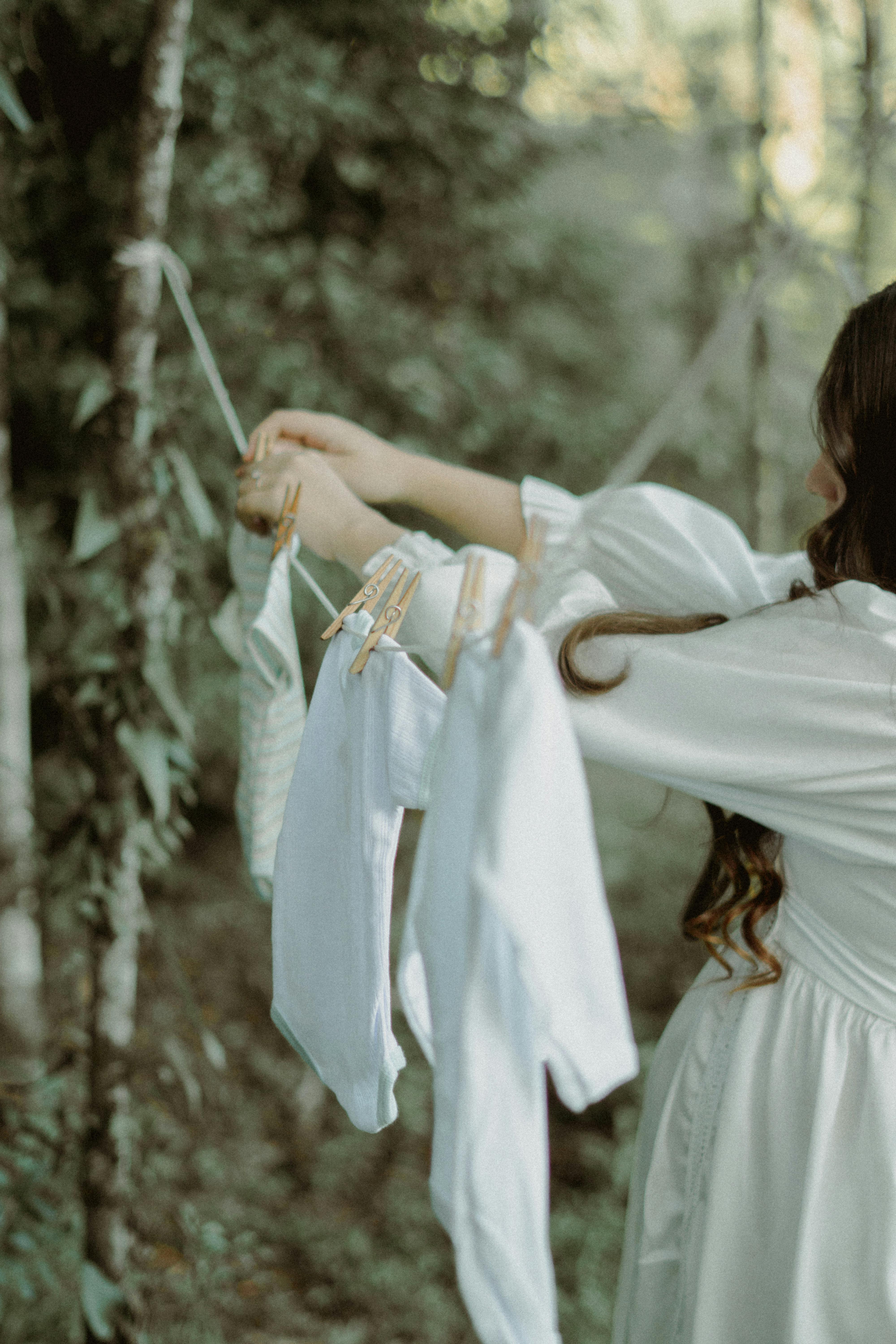 pregnant woman hanging baby clothes on a clothesline