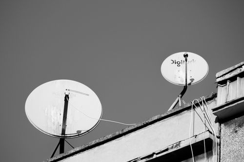 Free Monochrome image of two satellite dishes on a rooftop, representing communication technology. Stock Photo