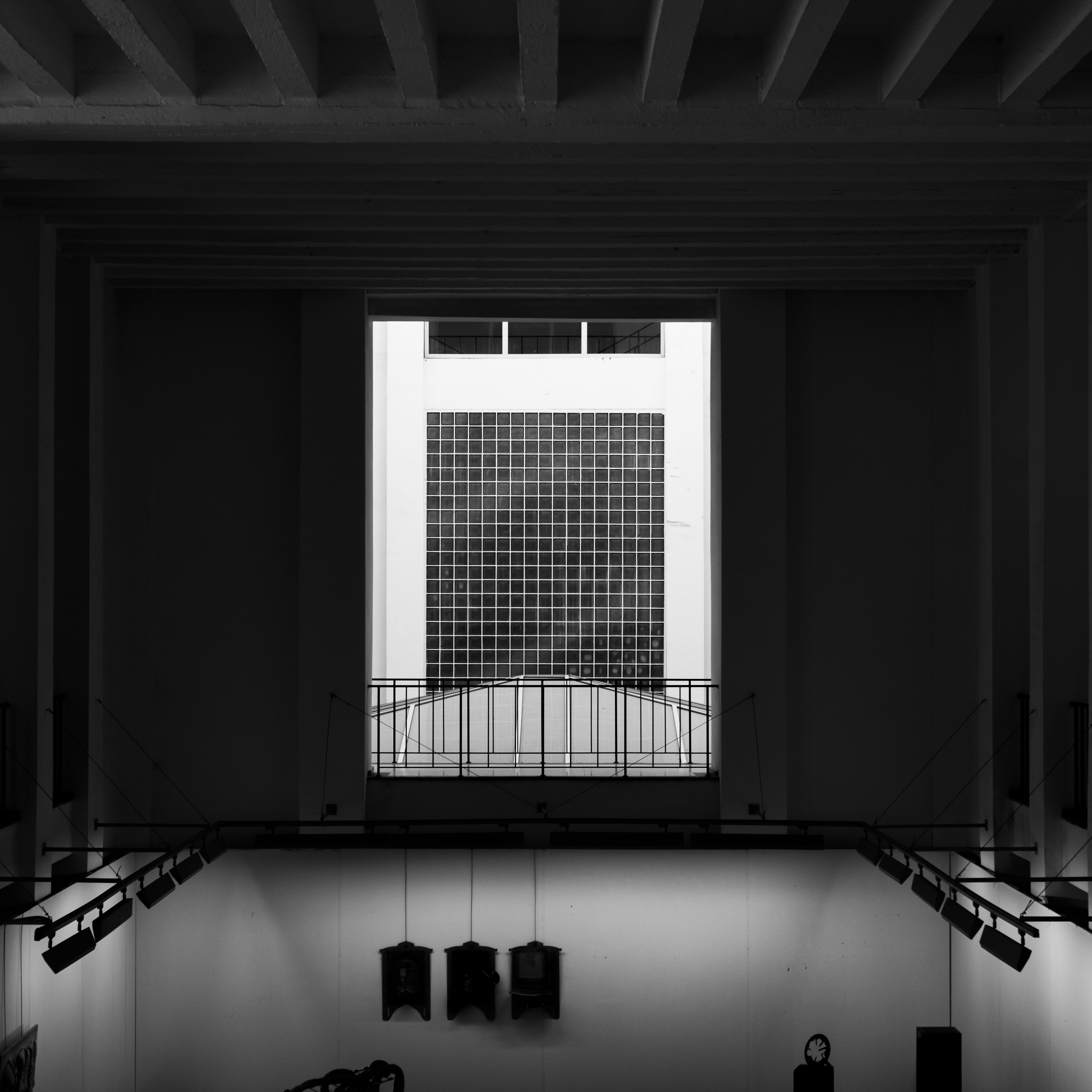 Black and white interior view of modern architectural space with grid window and geometric patterns.