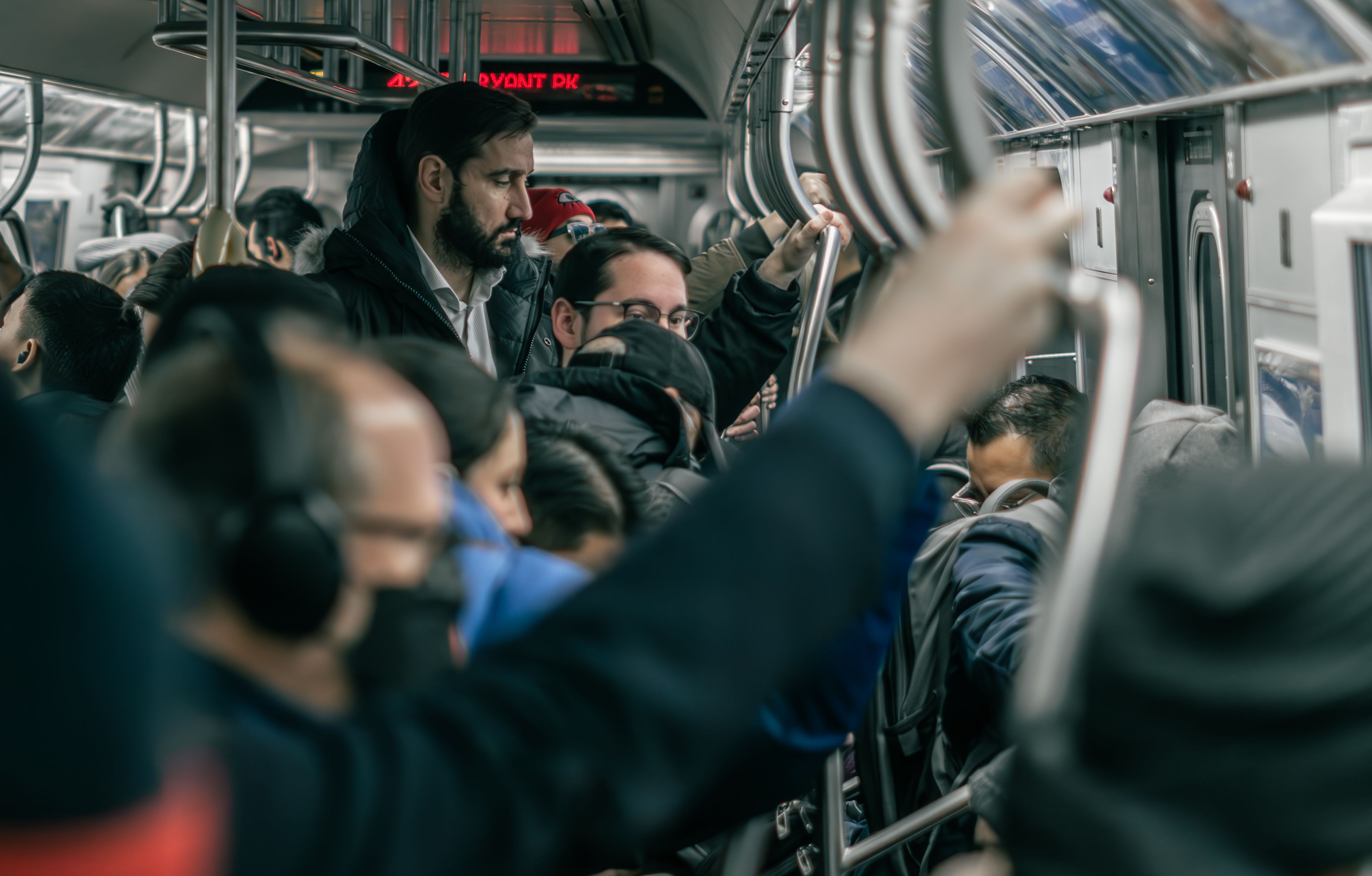 A dense crowd of commuters standing inside a busy subway train in New York City.