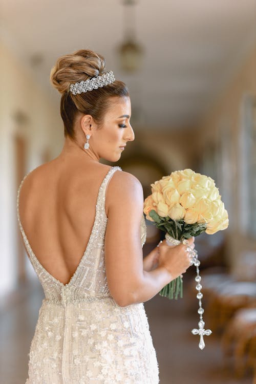 Back View of Bride Standing in Wedding Dress and with Flowers Bouquet