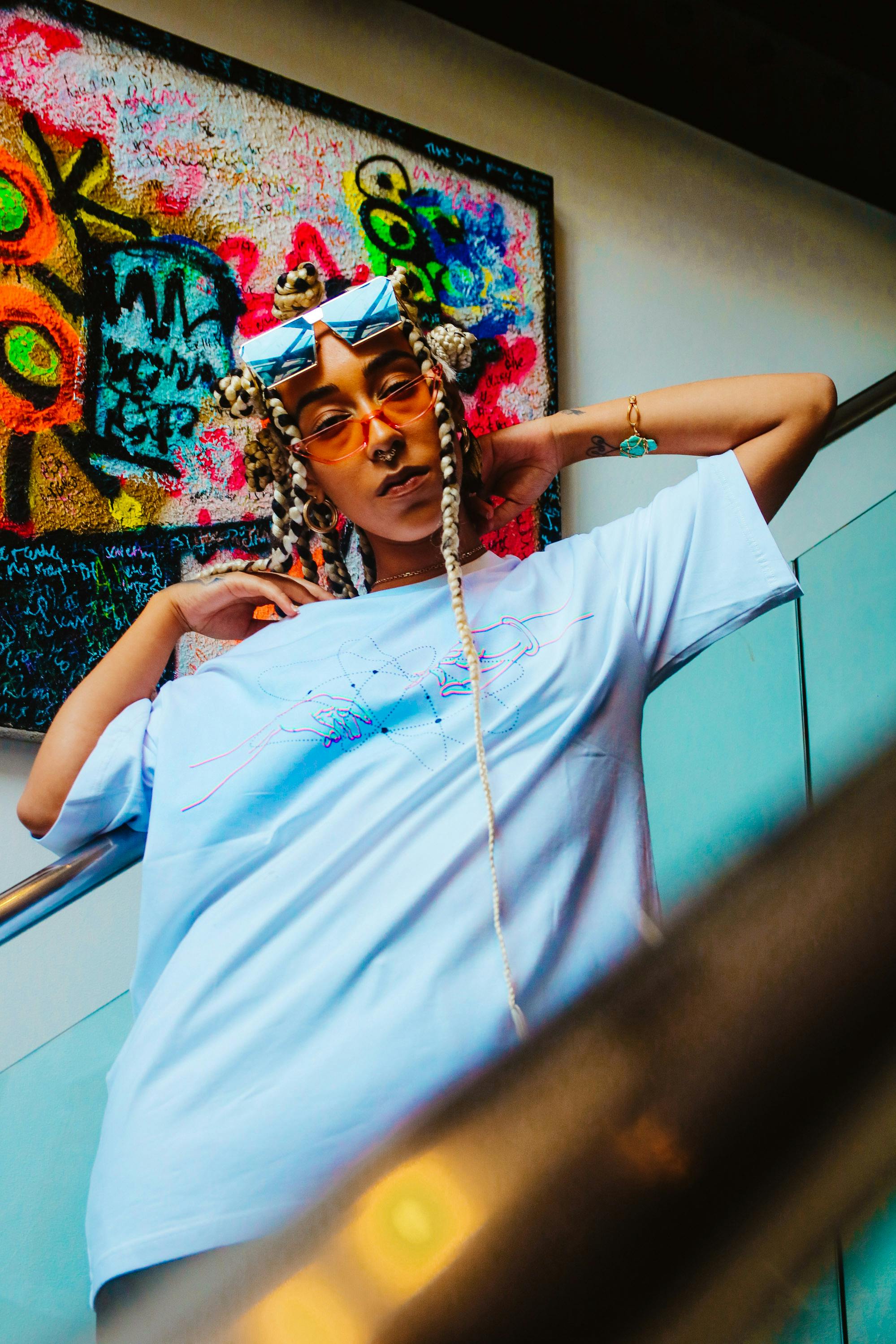 Stylish individual posing in streetwear against a colorful graffiti backdrop, exuding urban chic.