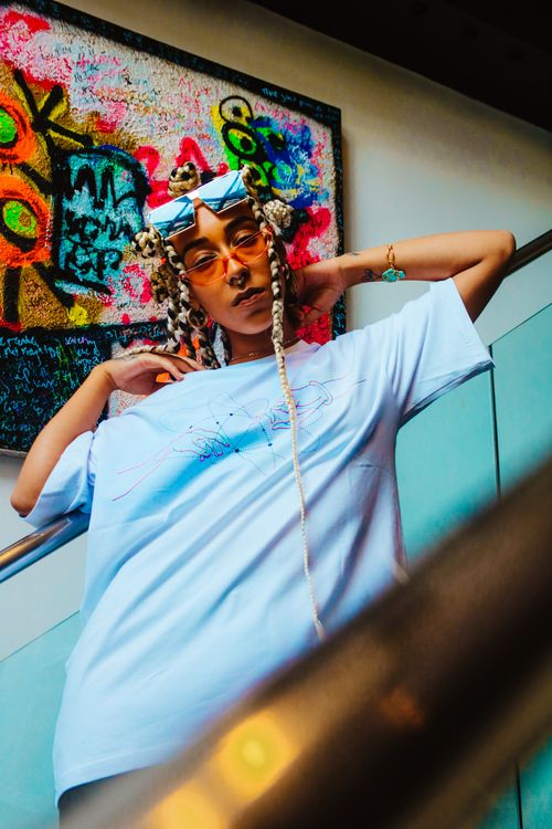 Free Stylish individual posing in streetwear against a colorful graffiti backdrop, exuding urban chic. Stock Photo