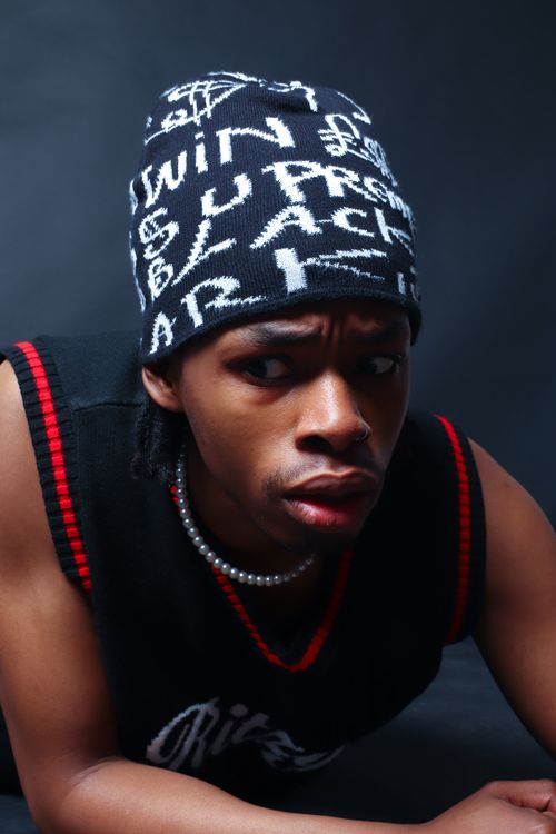 Free Stylish portrait of an African man wearing a graphic beanie and pearl necklace in a studio setting. Stock Photo