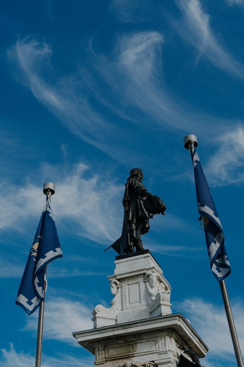 A statue of a man with flags in front of a blue sky