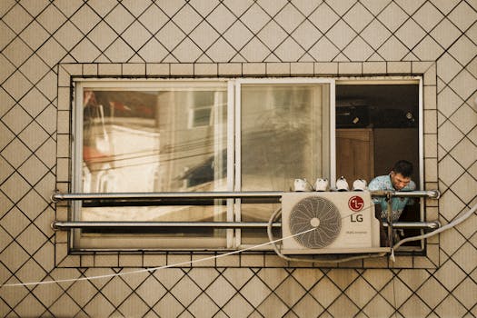 Man looks outside a window with an LG air conditioner unit visible, creating a reflective effect.
