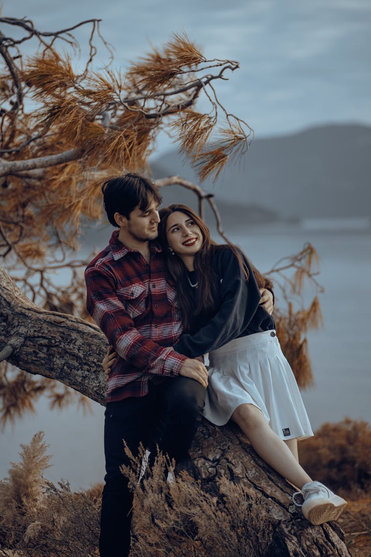 Young Couple Embracing On A Tree Trunk