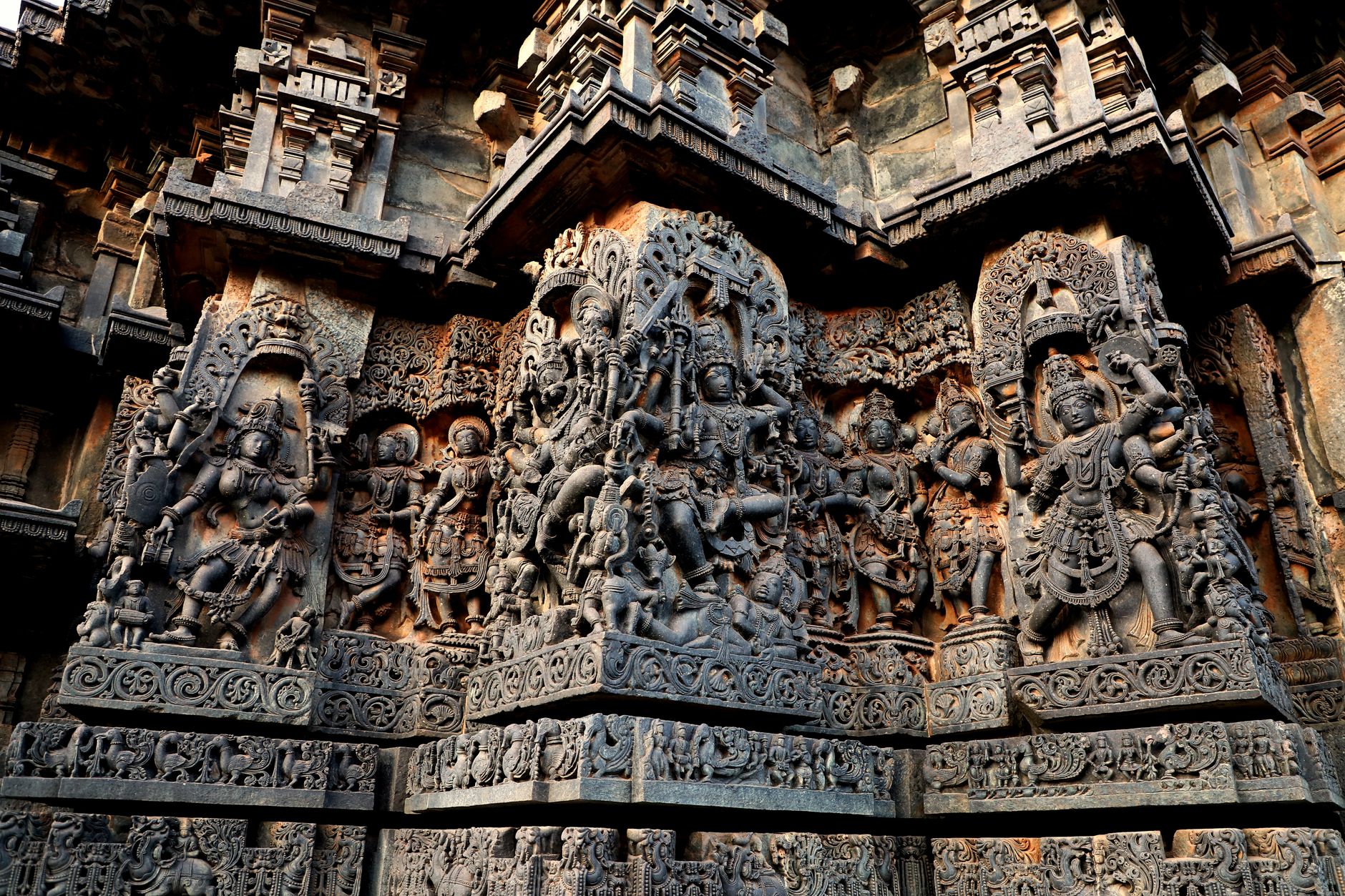 Detailed stone carvings from Hoysaleshwara Temple, India, showcasing Hindu deities and intricate designs.