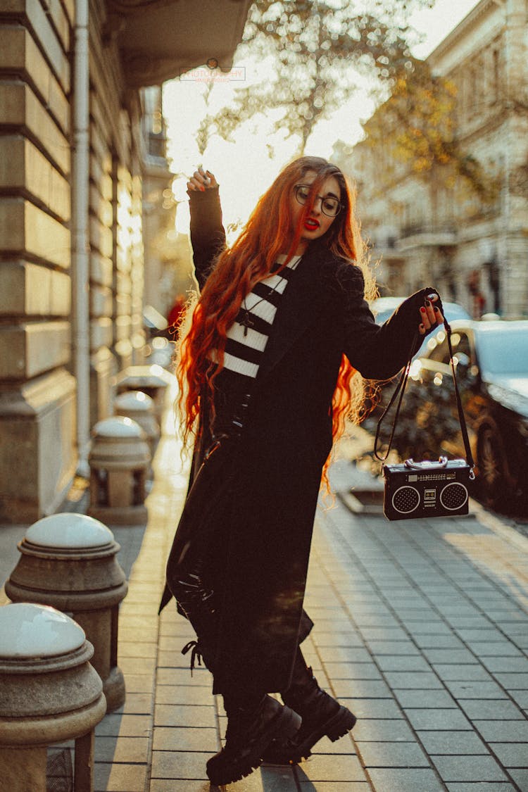 Young Woman Dancing On The Sidewalk With A Purse Looking Like A Retro Boombox