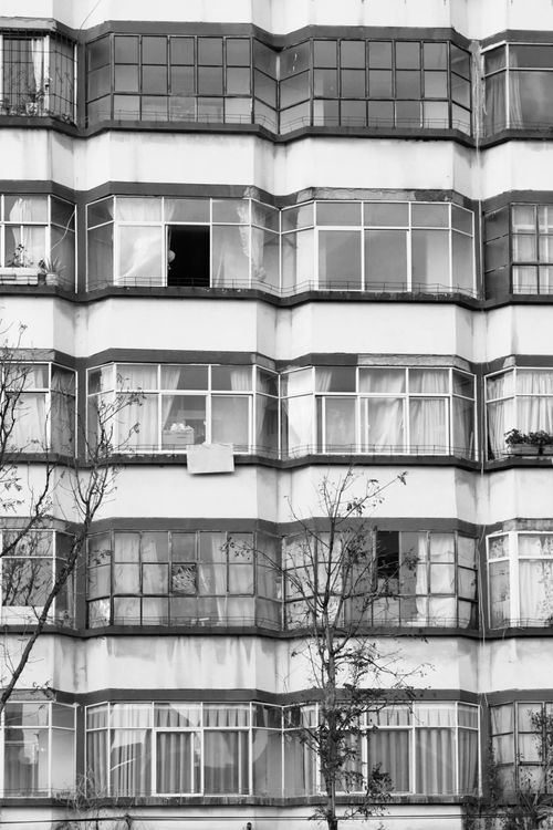 Free Black and white photo capturing urban residential building featuring glass balconies and windows. Stock Photo