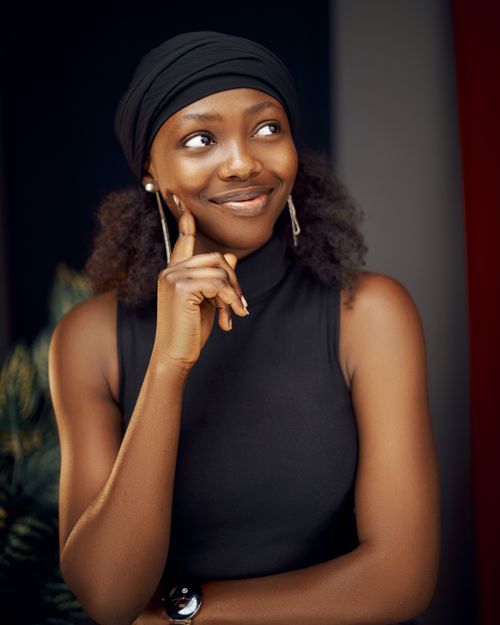 Free Beautiful black woman in a black tank top smiling thoughtfully. Fashion photography with a warm tone. Stock Photo