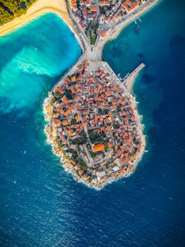 Breathtaking aerial view of Primošten peninsula in Croatia, surrounded by azure waters and vibrant rooftops.