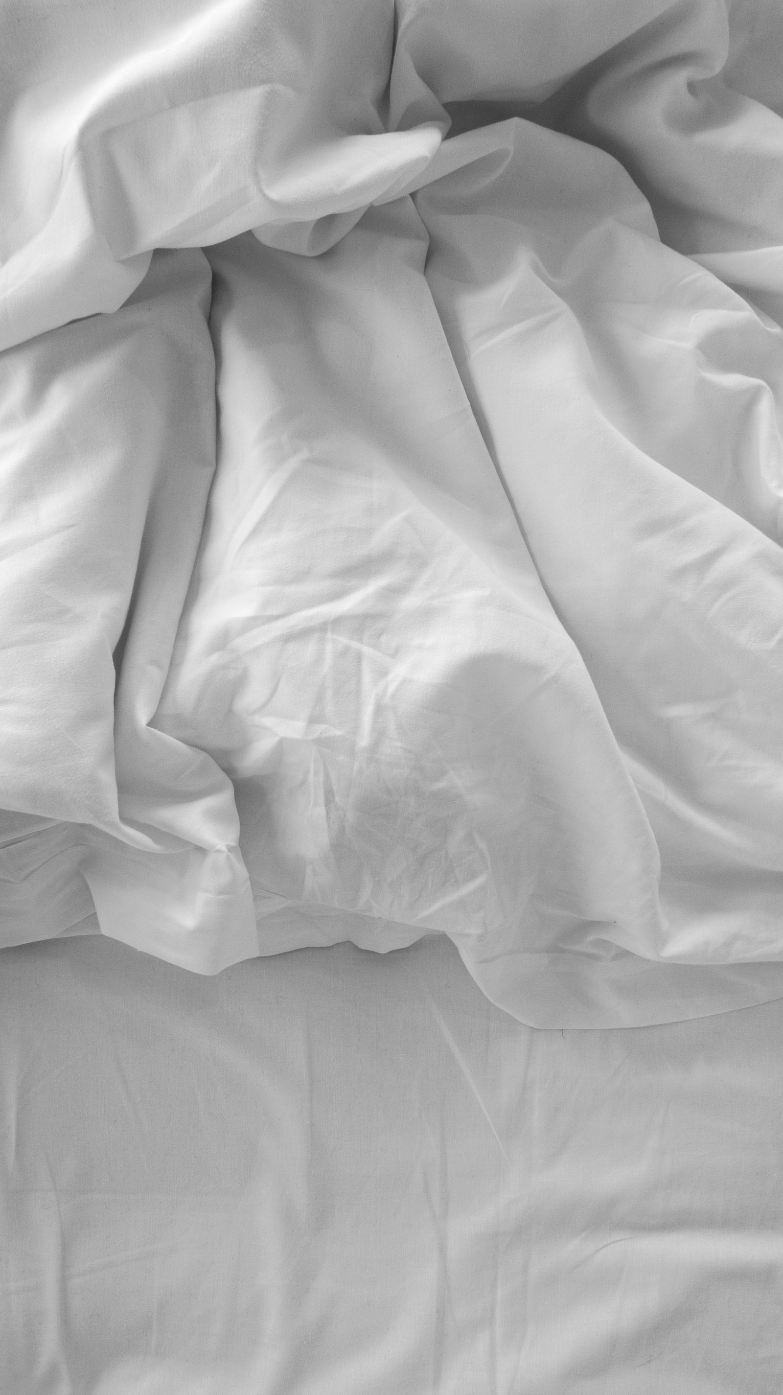 Soft white bedding arranged with relaxed folds in a peaceful bedroom