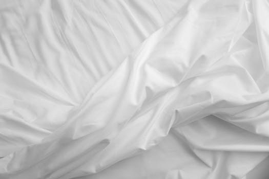 An elegant, close-up view of white satin sheets with a texture that evokes comfort and luxury.