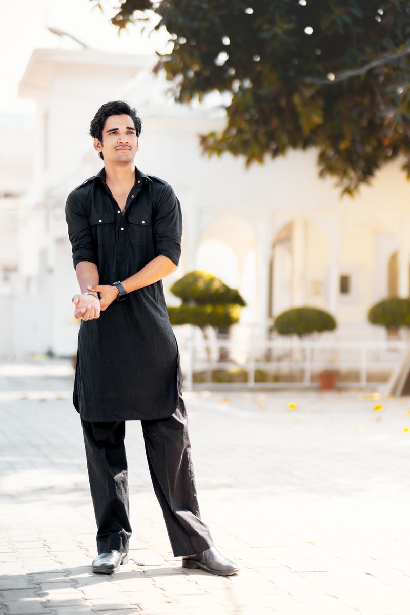 A man in a black kurta and matching loose trousers outdoors